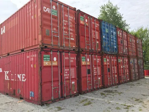Rows of used red and blue shipping containers stacked two high in a storage yard